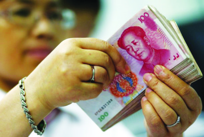 An employee counts yuan banknotes at a bank in Suining